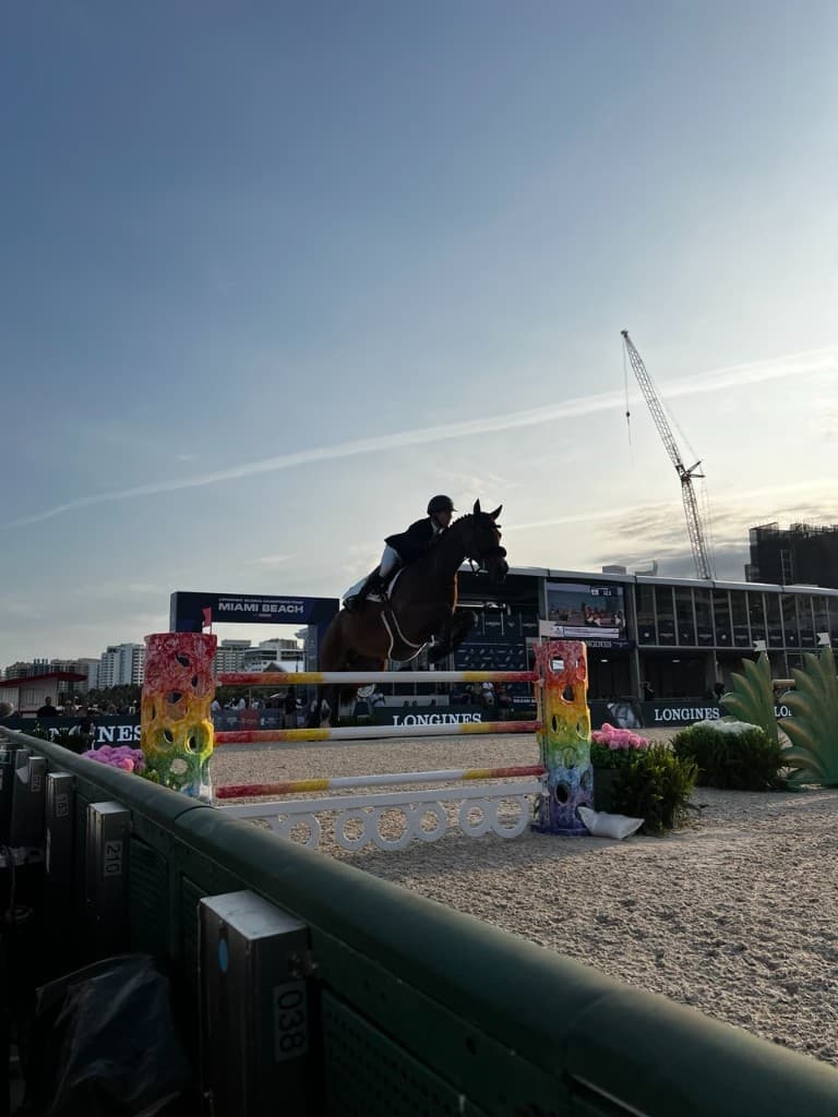 Horse and rider mid-jump over a colorful obstacle at Longines Global Champions Tour Miami Beach